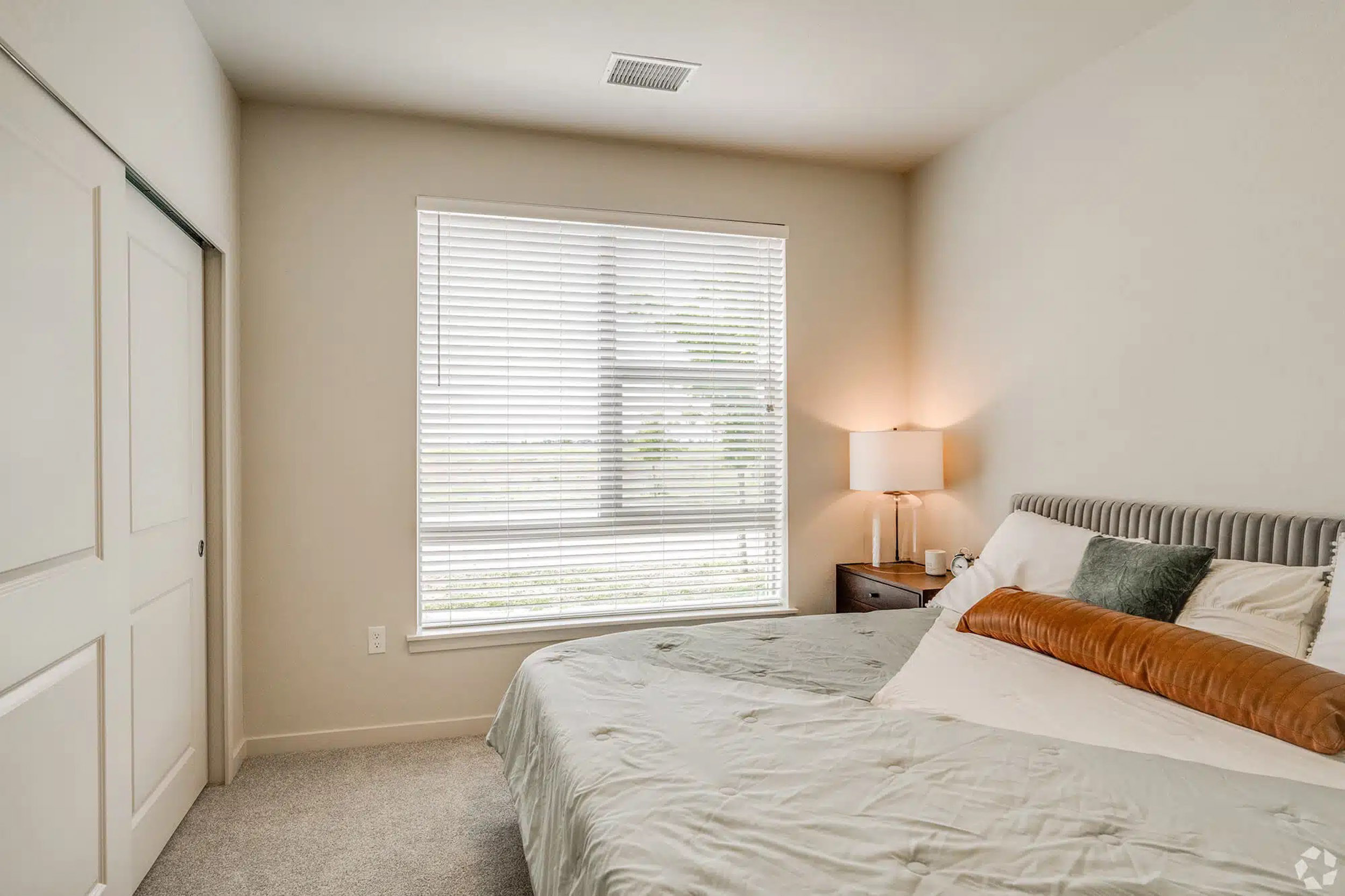 Bedroom with large window and bed facing closet