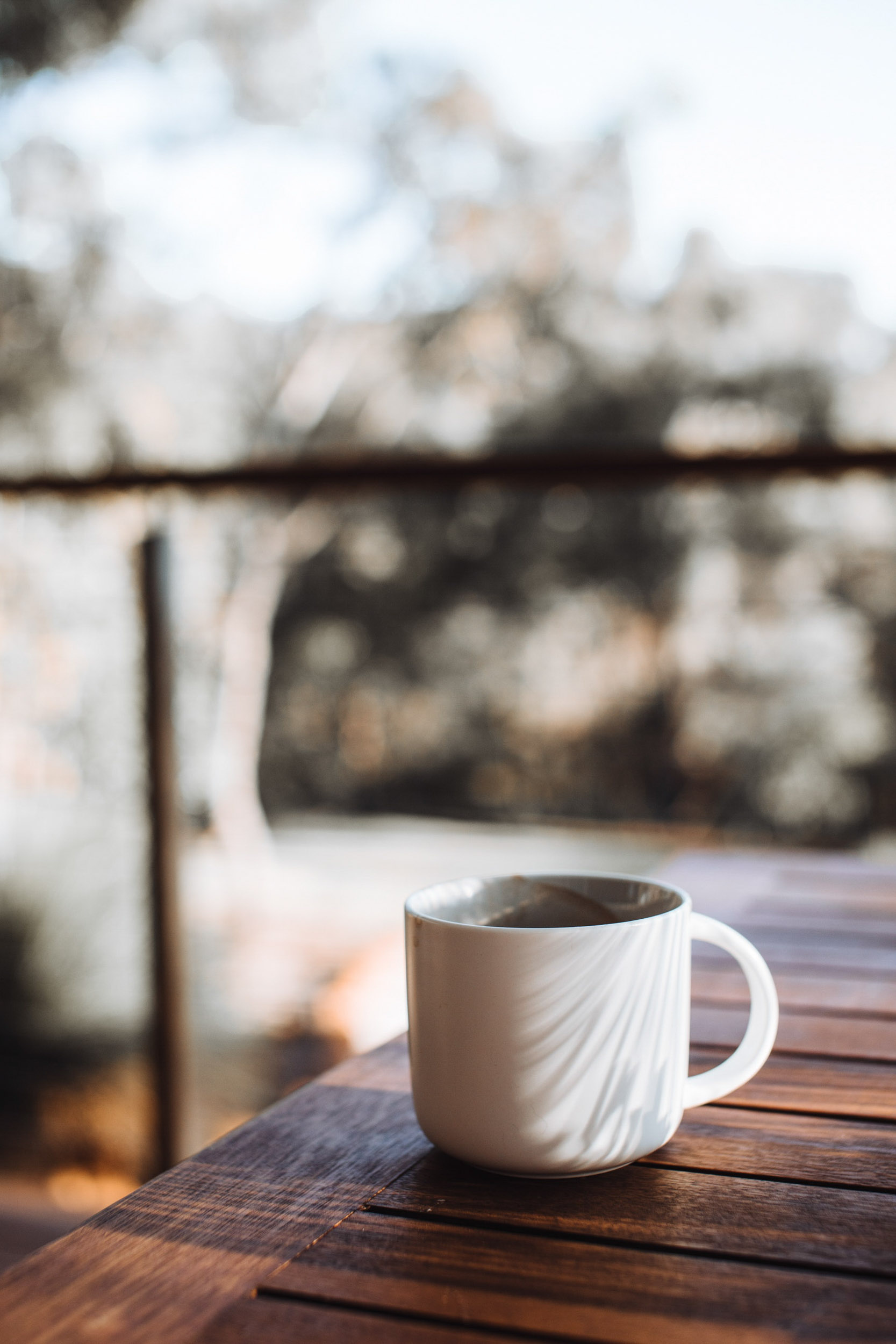 Mug of coffee on wood table outside