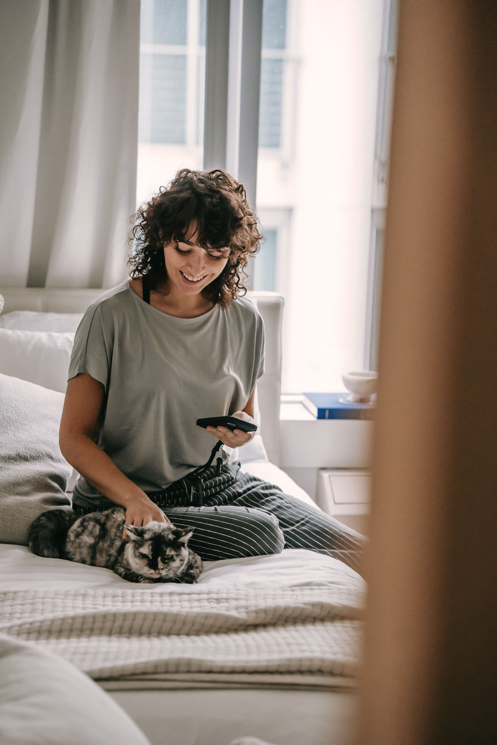 Woman petting cat on bed